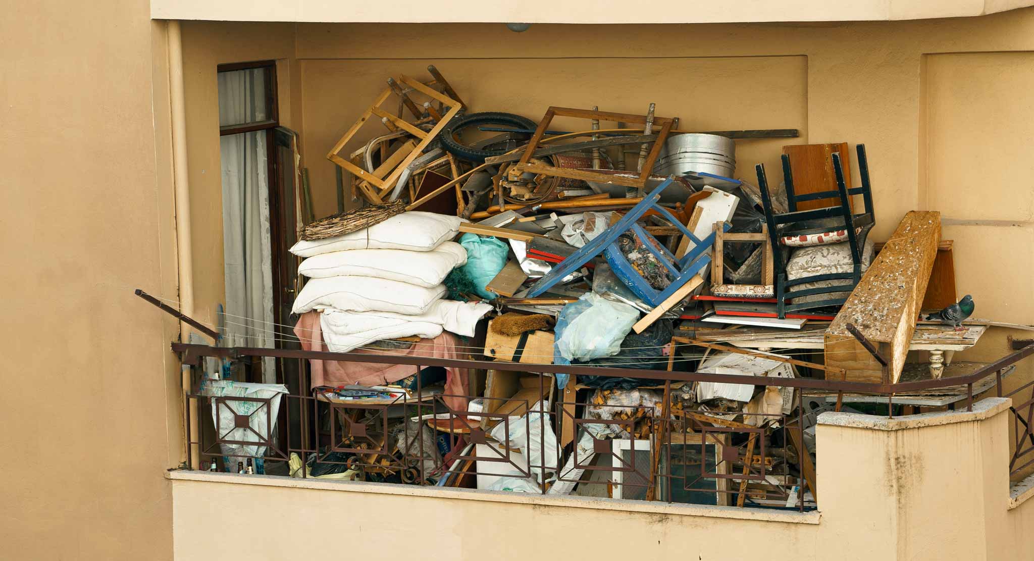 A severely cluttered residential room filled with high stacks of old newspapers, boxes, and miscellaneous household items requiring professional hoarding cleanouts in St. George Utah.